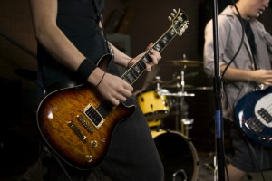 lifestyle portrait of two teenage males as they wildly practice their guitars with a band